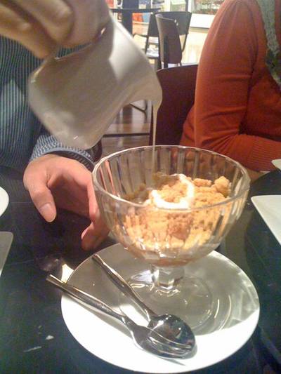 กำลังราดวนิลาซ้อสลงบน Apple Crumble ที่ ร้านอาหาร Sweet Hound พารากอน