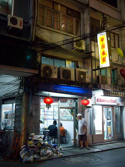 หน้าร้านเกี๊ยวจีนตอนกลางคืน เปิดไฟสว่าง ป้ายสีเหลือง ที่ ร้านอาหาร เกี๊ยวจีน (ภัตตาคารซันมูน)