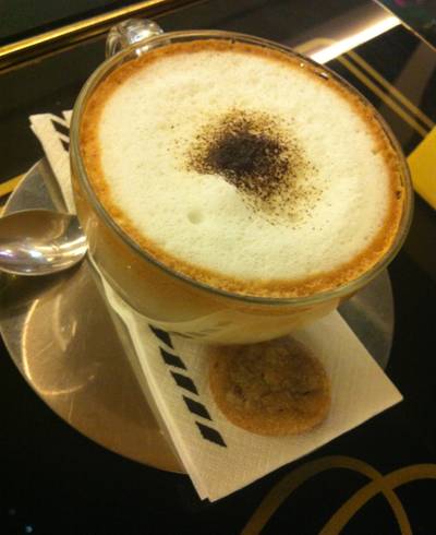 คาปูชิโน่ร้อน ที่มีคุ้กกี้มา 1 ชิ้น ที่ ร้านอาหาร Vanilla Brasserie Siam Paragon