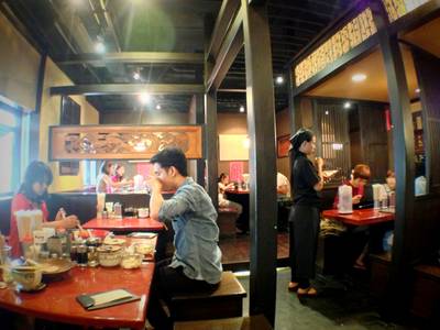 ทางซ้ายของภาพเป็นหน้าต่าง มีกระจกกันแอร์ออก มองไปเห็นรถที่จอด ที่ ร้านอาหาร Bankara Ramen
