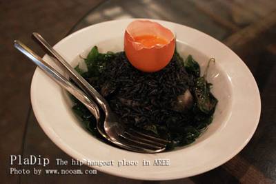 เป็นข้าวผัดหมึกดำ ข้างในจะเป็นกุ้ง ปลาหมึก และใบกระเพรา มาพร้อมกับไข่แดง ที่ ร้านอาหาร ปลาดิบ